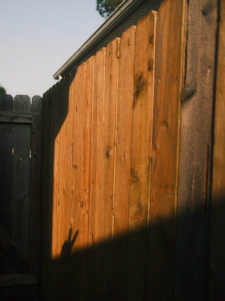 Sunlight casts a shadow on a wooden fence.